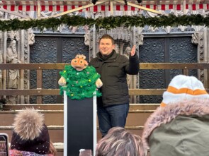 Der Bauchredner Sebastian Reich mit der Nilpferddame Amanda, die ein Tannenbaum-Kostüm trägt auf der Bühne vor der Frauenkirche.