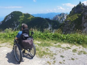 Kind im Rollstuhl vor Bergpanorama