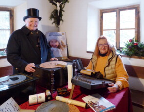 Klaus Halter und Helga Behr in einem Bauernhof-Stüberl mit historischen Musikinstrumenten.