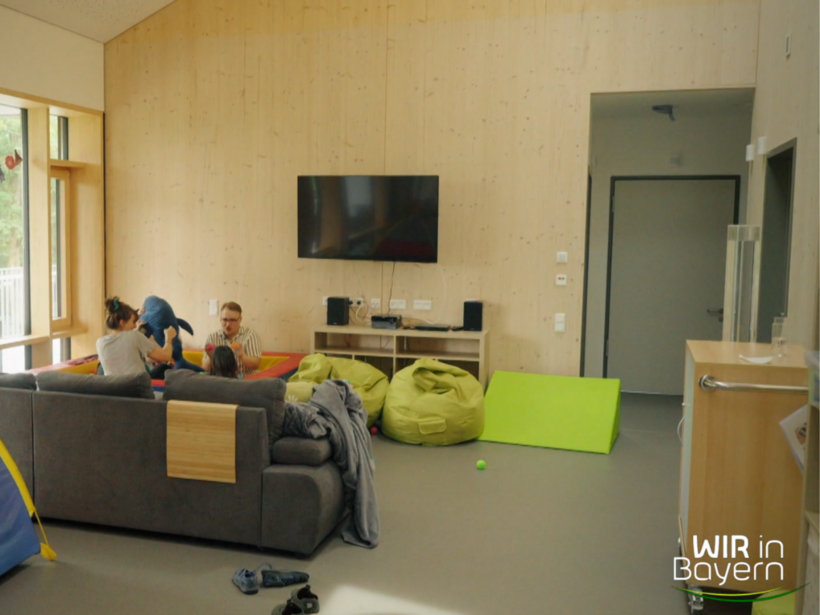 Sternstunden Bilanz : Kurzzeitpflegehaus "Haus Hummelchen". Hell eingerichteter Gemeinschaftsraum mit Holzverkleidung, großem Sofa, Fernseher und Sitzsäcken.