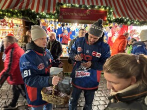 Zwei Spieler der Nürnberg Ice Tigers in Trikots beim Autogramme schreiben. 