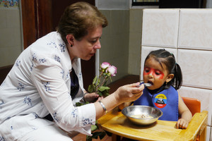 Frau füttert kleines Mädchen in Hochstuhl