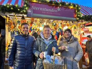 drei junge Männer von der Gruppe "Dorfrocker" vor dem Sternstunden-Stand