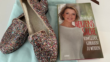 Schauspielerin Uschi Glas versteigert ein paar handgefertigte und ungetragene Schuhe und ein signiertes Exemplar ihres Buchs "Herzenssache". 