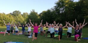 Gruppe von Sportbegeisterte beim Open-Air-Pilates auf einem Sportgelände