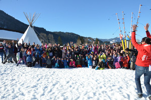 große Gruppe Kinder und Jugendliche knien oder stehen im Schnee und jubeln mit hochgestreckten Armen