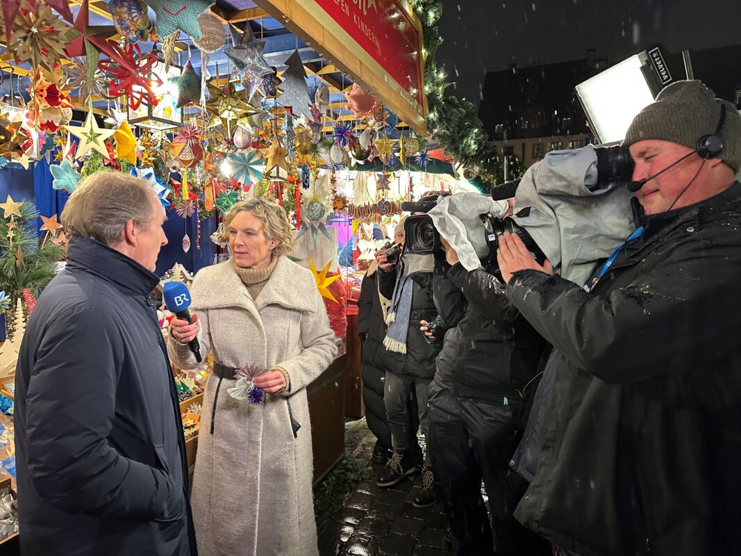 Julia Büchler interviewt Thomas Jansing vor dem Sternstunden-Stand. Rechts im Bild sieht man einen Kameramann vom BR mit der großen Kamera auf der Schulter. Er filmt das Interview.