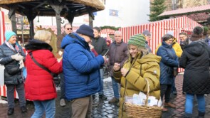 die Schlagersängerin Nicki umringt von Marktbesuchern, wie sie gerade ein Autogramm gibt