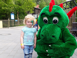 Mädchen mit Drachenmaskottchen im Freizeitpark