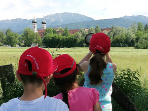 Drei Kinder (von hinten) beobachten das Kloster 