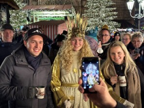 Das Nürnberger Christkind mit zwei Marktbesuchern werden gerade fotografiert. Im Vordergrund ist das Bild auf dem Handy zu sehen. 