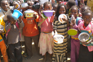 Kinder bei der Schulspeisung in Ouagadougou zeigen ihre Gefäße mit Essen