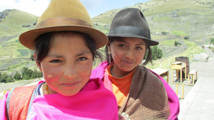 Zwei Mädchen mit Hüten gucken in die Kamera, im Hintergrund Anden