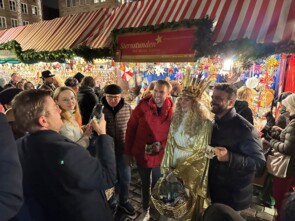 Der Fotograf Markus König lehnt sich weit nach hinten um das Christkind mit zwei Marktbesuchern zu fotografieren.