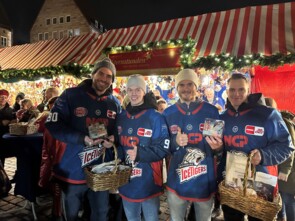 Vier Spieler der Nürnberg Ice Tigers nebeneinander, sie zeigen zwei volle Spendendosen