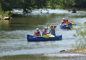 Kinder und Erwachsene die Spaß beim Kanufahren am Fluss haben