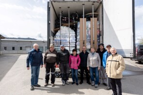 Eine Gruppe des Helferkreises steht vor einem vollbeladenen LKW.